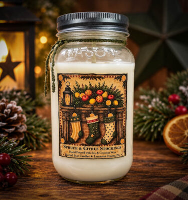 Spruce & Citrus Stockings 24 oz Soy and Coconut Wax Jar Candle with a vintage Christmas stocking label, displayed on a rustic wooden table with festive evergreen greenery, pinecones, and warm holiday lights.