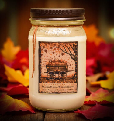 Falling Leaves 16 oz candle in mason jar with folk art label featuring a wagon of pumpkins and falling autumn leaves