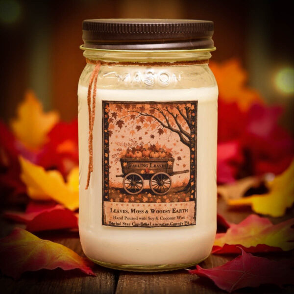 Falling Leaves 16 oz candle in mason jar with folk art label featuring a wagon of pumpkins and falling autumn leaves