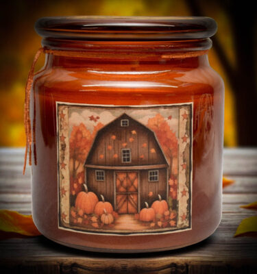 Amber jar candle with a folk art red barn label, featuring pumpkins and fall leaves.
