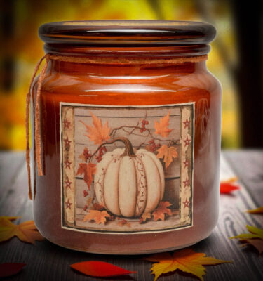 Amber jar candle with a white pumpkin and maple leaf folk art label, perfect for fall farmhouse décor.