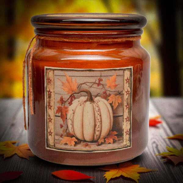 Amber jar candle with a white pumpkin and maple leaf folk art label, perfect for fall farmhouse décor.