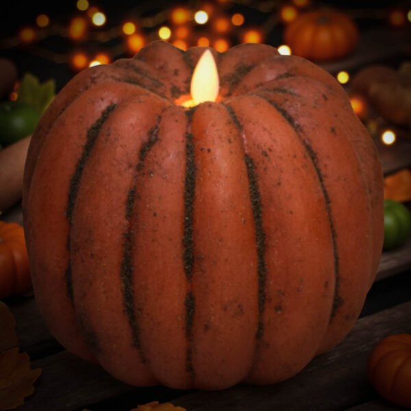 “Large pumpkin moving flame candle with rustic cinnamon spice grunge glowing warmly among autumn leaves”