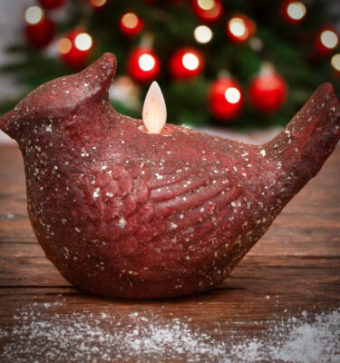 Cardinal moving flame candle with cinnamon-scented wax and mica glitter on wooden table