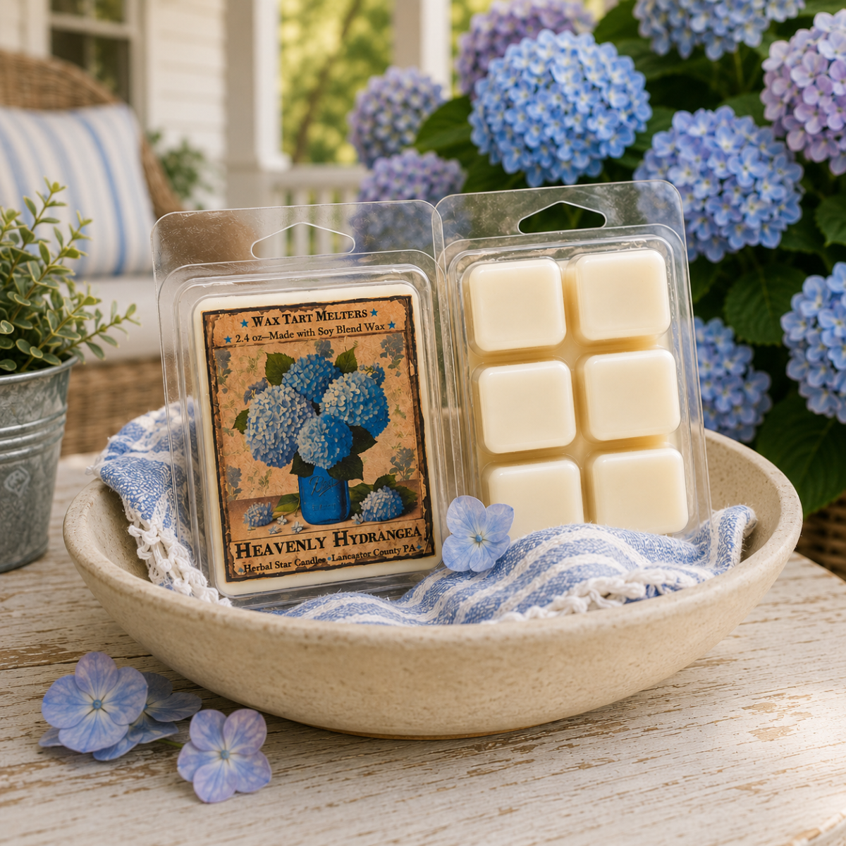 Heavenly Hydrangea wax tart melters with soft floral fragrance, displayed in a ceramic bowl among blooming hydrangeas on a cottage-style porch.