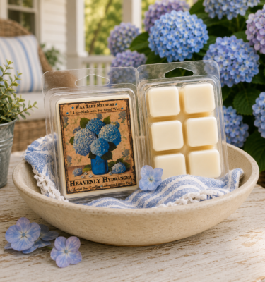 Heavenly Hydrangea wax tart melters with soft floral fragrance, displayed in a ceramic bowl among blooming hydrangeas on a cottage-style porch.